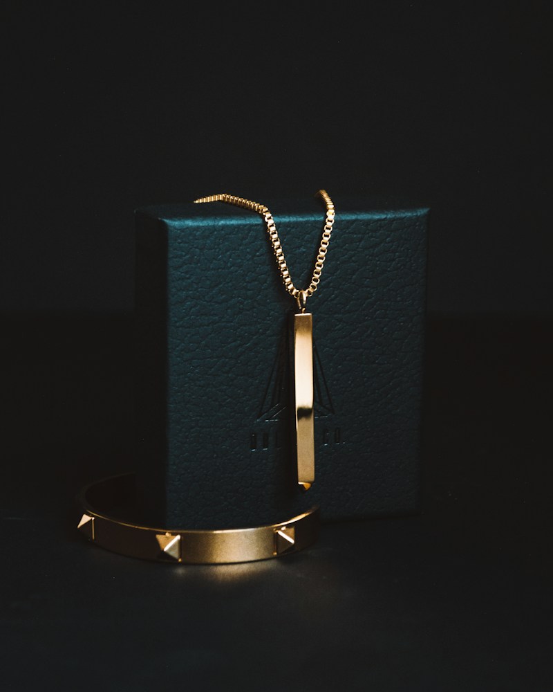 Gold pendant necklace and bracelet against a dark backdrop in a mock Meta ad